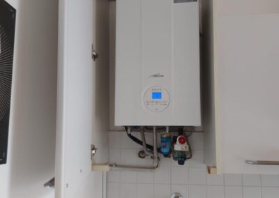 Tecnico che installa e manutiene due caldaie a condensazione Vaillant, Baxi o Ariston, impianto moderno di riscaldamento domestico