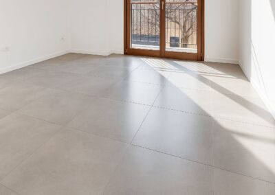 Stanza luminosa con pavimento in ceramica moderna, piastrelle grandi e posa rettificata